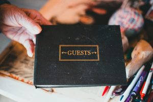 a person holding a black book with the word guests on it